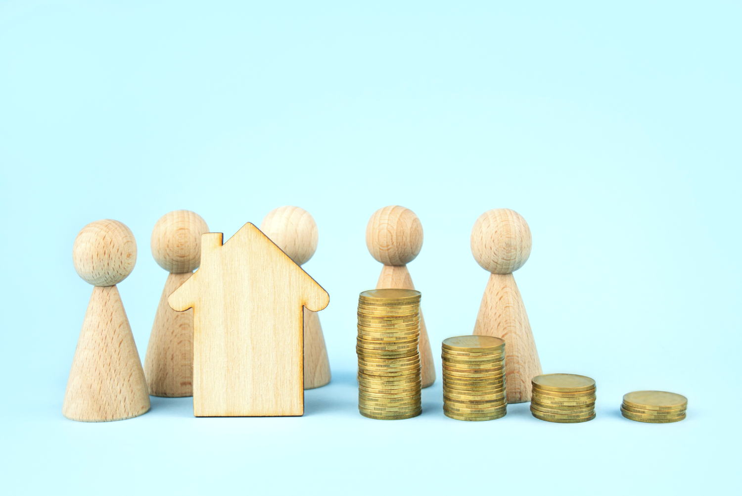 Representación de personas con muñecos de madera y una casa, a lado de monedas