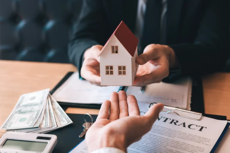 Manos entregando una maqueta de casa a otra mano