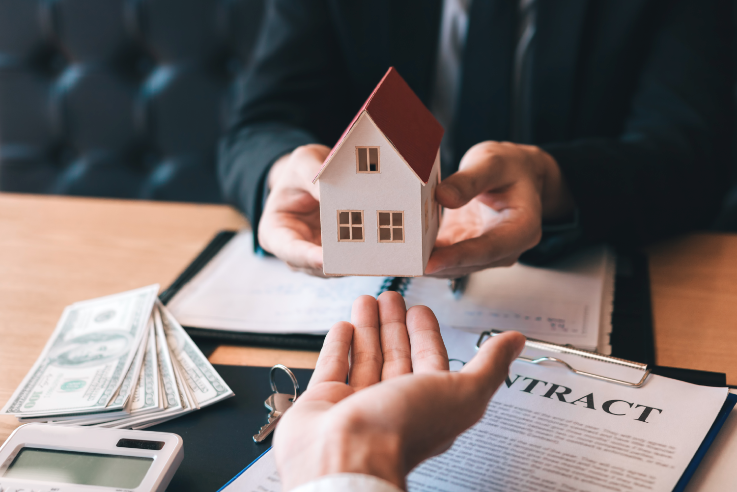 Manos entregando una maqueta de casa a otra mano